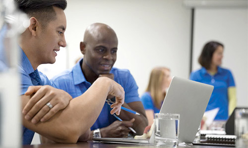 two workers consulting over laptop