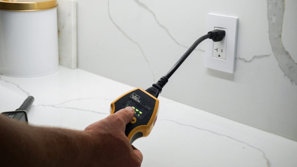 An electrical inspector using an assessment tool on electrical sockets